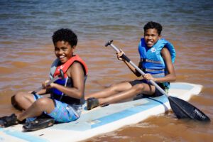 Two campers at Camp Hope on top of a paddle board rowing on a lake